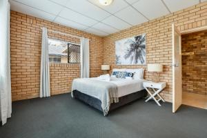 1 dormitorio con cama y pared de ladrillo en Bradman21, en Maroochydore