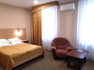 een slaapkamer met een bed, een stoel en een raam bij Vizit Hotel in Perm