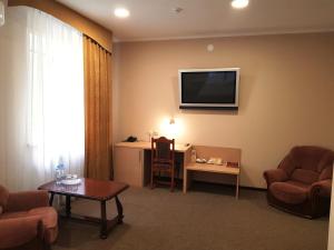- un salon avec 2 chaises et une télévision murale dans l'établissement Vizit Hotel, à Perm