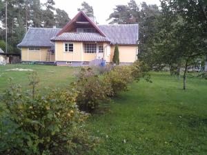 uma casa amarela com um telhado vermelho num quintal em Koidu Homestay em Haapsalu