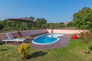 a swimming pool in a yard with an umbrella at Ferienhaus Joy in Ližnjan