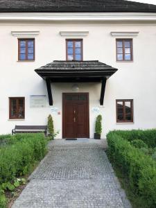 a white house with a brown door and a stone walkway at Zamkowa, Pokoje Gościnne in Kazimierz Dolny