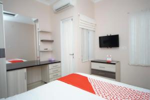 Talang KelapaにあるSuper OYO 270 Madinah Residence Syariahのベッドルーム1室(ベッド1台付)、キッチン(テレビ付)