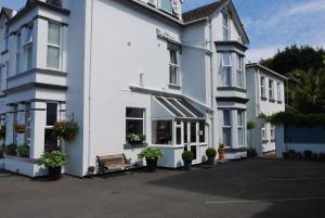 a white building with a bench in front of it at Redlands in Brixham