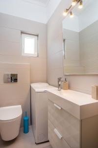 a bathroom with a toilet and a sink and a mirror at Mythos Luxury Villa in Faliraki