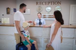une famille debout à un comptoir dans une cuisine dans l'établissement Sunny Castle Hotel - All Inclusive, Beach and Free parking, à Kranevo 102 autres photos
