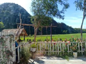 a white fence with a garden and a hill in the background at Phong Nha Rice Field Homestay in Phong Nha