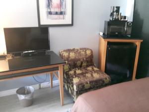 a room with a tv and a chair and a desk at Fuller Lake Chemainus Motel in Chemainus