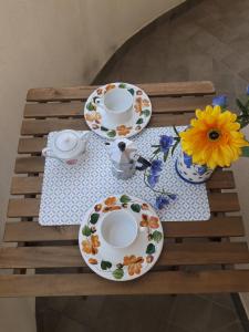 a table with plates and cups and flowers on it at La bomboniera in Imperia