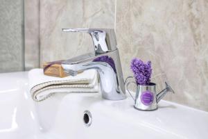 a sink with a faucet and a cup of purple flowers at Apartment Vivien in Crikvenica +44 photos