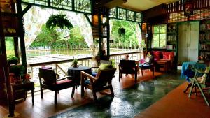 een kamer met stoelen, tafels en ramen bij Saikaew Resort in Chiang Rai