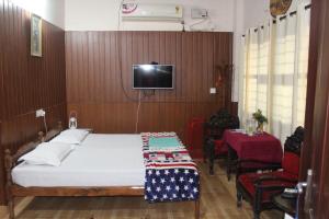 a bedroom with a bed and a tv on a wall at West Wind Homez - Home Stay in Cochin