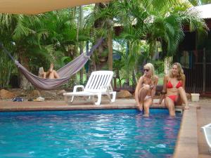 two women in bathing suits sitting in a swimming pool at Cable Beach Backpackers in Broome