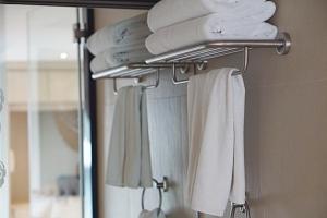 a towel rack with towels on it in a bathroom at Aspira G Sukhumvit 33 in Bangkok