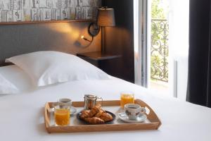 a tray of food with drinks and croissants on a bed at Hôtel Bristol Reims in Reims