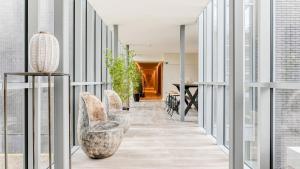 a hallway with chairs and a table and windows at Hotel Acropolis " Op het sportiefste park van de kust " in Middelkerke