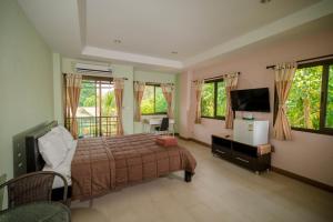 a bedroom with a bed and a tv and windows at Banlanna Hotel Lampang in Lampang