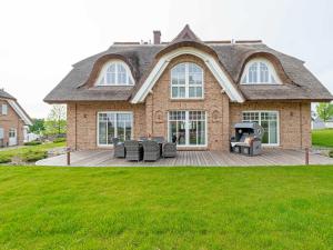 a house with a deck with furniture on it at Strandhaus 6 "Düne" in Lobbe mit Meerblick, Kamin, Sauna in Lobbe