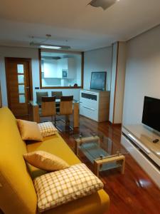 sala de estar con sofá amarillo y mesa en Apartamento Edificio Plaza Gran Vía en Salamanca