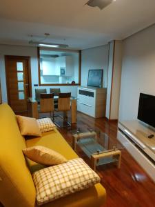 ein Wohnzimmer mit einem gelben Sofa und einem Tisch in der Unterkunft Apartamento Edificio Plaza Gran Vía in Salamanca