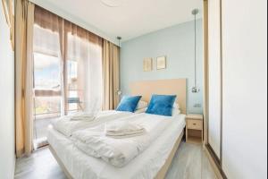 ein Schlafzimmer mit einem großen weißen Bett mit blauen Kissen in der Unterkunft Unique Motlawa Riverbank Apartment in Danzig