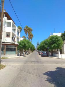 an empty street with palm trees and a white building at Iridas house in Kos Town