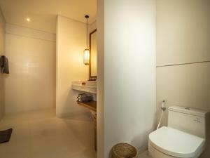 a white bathroom with a toilet and a sink at Bumbak Park Villas in Canggu
