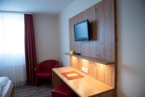 a hotel room with a desk with a tv on the wall at Gasthaus Stroh in Buchholz