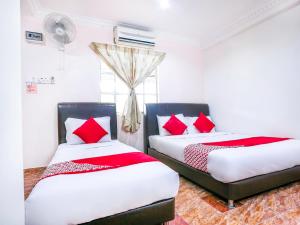 two beds in a room with red pillows at D' Anjung Inn in Tangkak