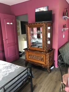 1 dormitorio con tocador de madera y pared rosa en La romance, en Le Breuil-en-Auge