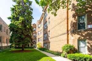 an apartment building with a tree in a yard at Lively 2BR Apt in Lincoln Square - Eastwood 47-1 in Chicago