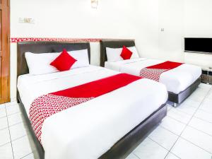 two beds with red pillows in a room at D' Anjung Inn in Tangkak