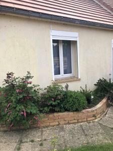 una ventana de una casa con flores delante en La romance, en Le Breuil-en-Auge