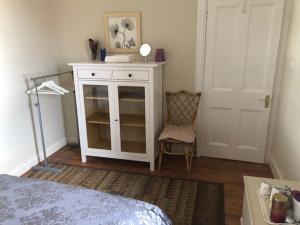 a bedroom with a bed and a white cabinet and a door at Lynburn Country Retreat in Biggar