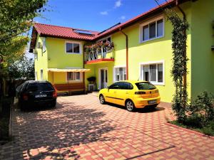 two cars parked in front of a yellow house at Casa Nelu Pescaru in Mahmudia