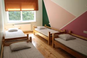 a room with three beds and a window at Liepu Hostelis in Liepāja