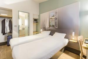 2 letti in una camera d'albergo con specchio di B&B HOTEL Montpellier Vendargues a Saint-Aunès
