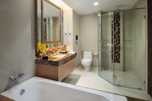 a bathroom with a tub and a sink and a toilet at The Berkeley Hotel Pratunam in Bangkok