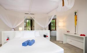 a white bedroom with a white bed and a desk at Sandies Baobab Beach Zanzibar in Nungwi