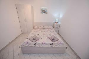 um quarto com uma cama com lençóis e almofadas cor-de-rosa em Apartman Marcela em Rab