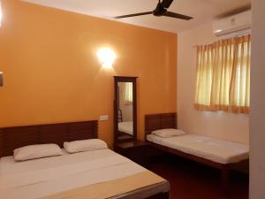 two beds in a room with a mirror and a ceiling fan at Shiva Rest Katharagama in Kataragama