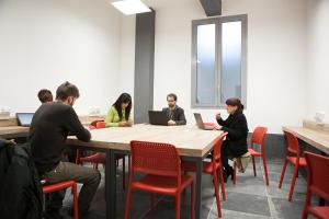 a group of people sitting at a table with laptops at Ostello Alfieri 2 in Turin