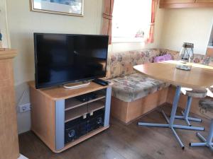 sala de estar con TV, sofá y mesa en Caravanverhuur Zeeland en Wemeldinge