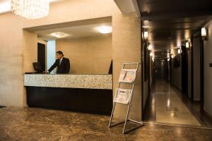 a man standing at a counter in a lobby at Diplomat, Chanakyapuri New Delhi- A Boutique Hotel in New Delhi