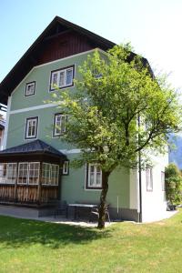 ein grünes Gebäude mit einem Baum davor in der Unterkunft Gingin- rooms in Hallstatt