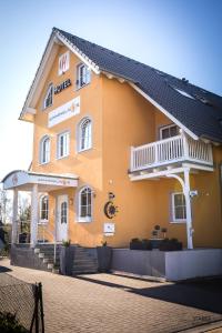 ein großes gelbes Gebäude mit Balkon in der Unterkunft Hotel Garni Sonnenklahr in Göhren