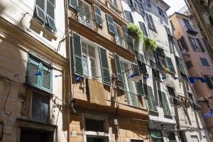 un bâtiment avec des fenêtres vertes à volets sur une rue dans l'établissement Sui tetti del centro di Genova by Wonderful Italy, à Gênes