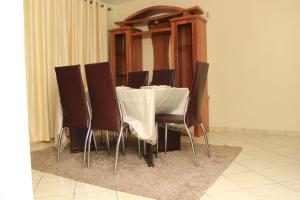 uma mesa com cadeiras castanhas e uma toalha de mesa branca em Essy's Apartments Nakuru with pool & GYM em Nakuru