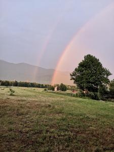 a rainbow in the sky over a field at House Mara in Korenica