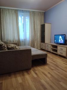 Habitación con cama, TV y sofá. en 2 к квартира между двумя станциями метро Студенческая и Академика Павлова en Járkov